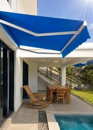 Store banne bleu déployé au-dessus d'une terrasse avec piscine
